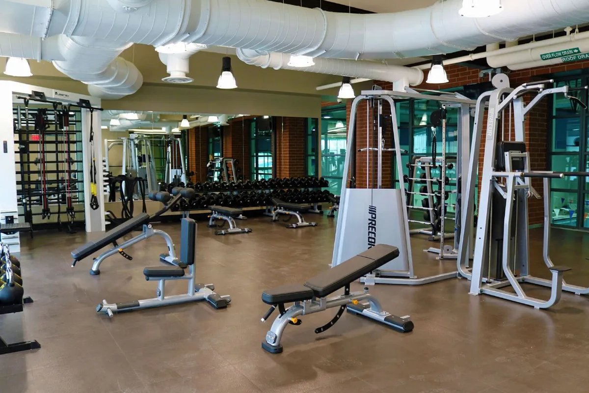 A modern gym interior with weight lifting equipment, exercise benches, and mirrored walls. The setting is bright, well-equipped, and motivational, inviting residents to engage in fitness routines or classes.